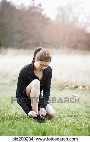 Picture - Asian woman tying her shoes. Fotosearch