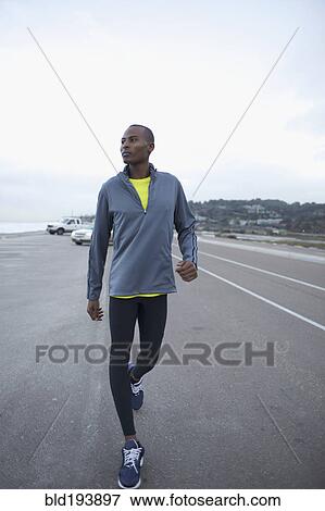 Stock Photo - Athletic Black man walking along road. Fotosearch