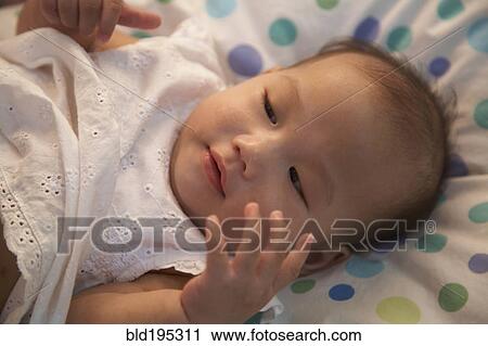 Stock Image - Baby girl laying in bed. Fotosearch