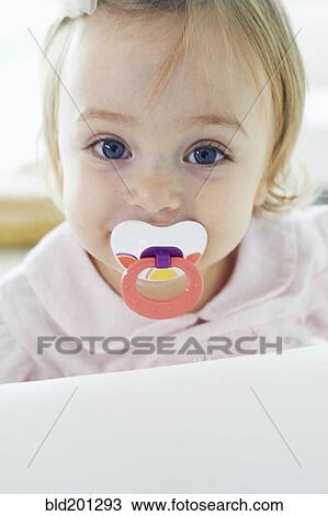 Stock Image - Baby girl sucking pacifier. Fotosearch