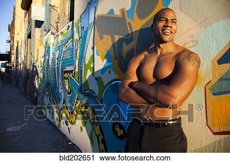 Stock Image - Bare chested African American man standing on city street. Fotosearch