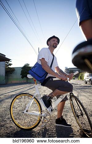 Stock Image - Bicycle messenger stopping on city street. Fotosearch