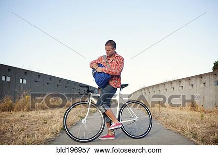 Stock Photo - Bicycle messenger stopping on urban path. Fotosearch
