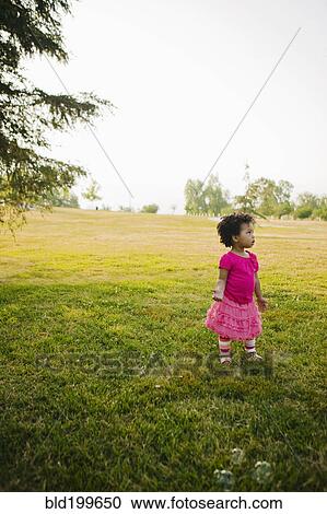 Stock Image - Black baby girl standing in park. Fotosearch