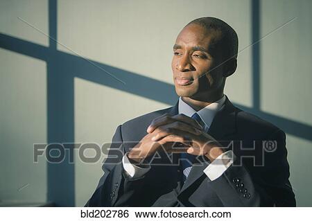Black businessman sitting at desk View Large Photo Image Stock Photograph - Black businessman sitting at desk. Fotosearch