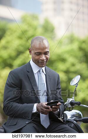Black businessman sitting on scooter text messaging View Large Photo Image Stock Image - Black businessman sitting on scooter text messaging. Fotosearch