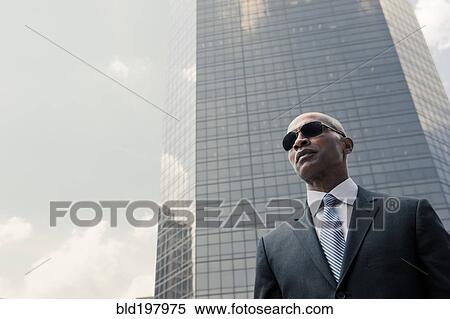 Stock Photography - Black businessman standing near highrise. Fotosearch