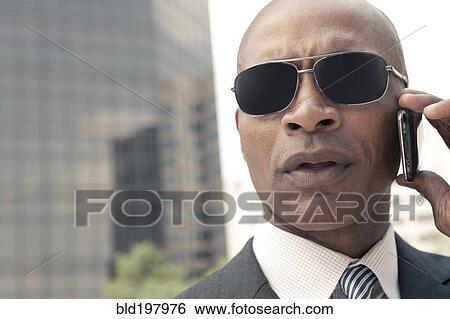 Stock Photograph - Black businessman talking on cell phone outdoors. Fotosearch
