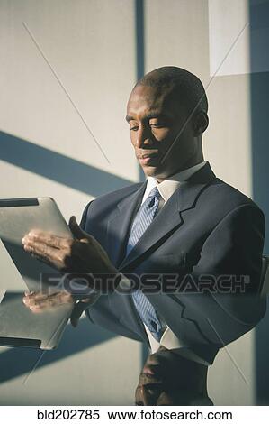 Stock Photography - Black businessman using tablet computer. Fotosearch