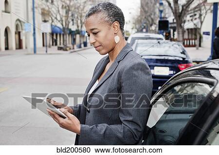Stock Image - Black businesswoman using digital tablet outdoors. Fotosearch