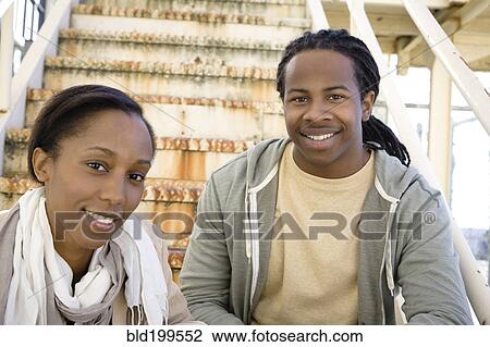 Stock Image - Black couple sitting on staircase. Fotosearch