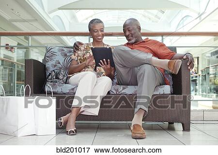 Stock Photo - Black couple using digital tablet in shopping mall. Fotosearch