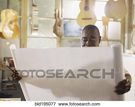 Black craftsman in guitar workshop looking at blueprints View Large Photo Image Stock Photo - Black craftsman in guitar workshop looking at blueprints. Fotosearch