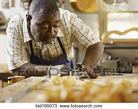 Stock Image - Black craftsman working in workshop. Fotosearch