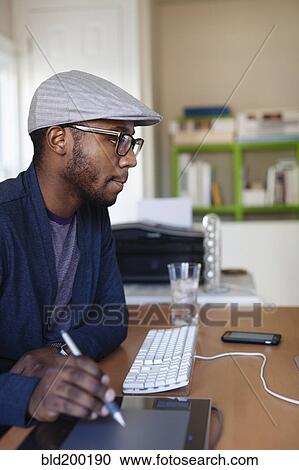 Stock Image - Black designer working at desk. Fotosearch