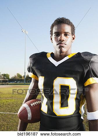 Stock Photo - Black football player holding football. Fotosearch