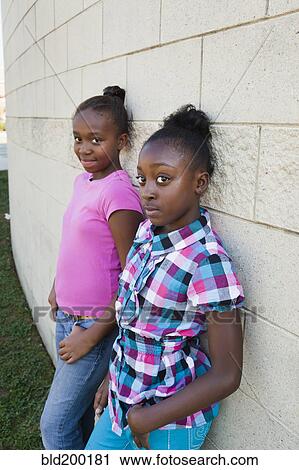 Stock Image - Black girls leaning against wall. Fotosearch