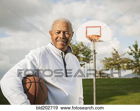 Stock Photo - Black man carrying basketball. Fotosearch