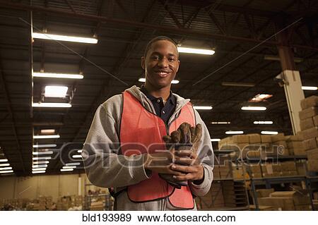 Stock Photo - Black man in reflector-vest in warehouse. Fotosearch