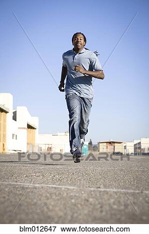 Stock Photo - Black man running in parking lot. Fotosearch