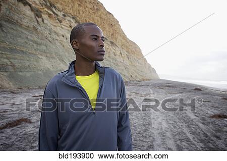 Stock Image - Black man standing on beach. Fotosearch