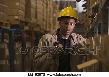 Stock Photo - Black man with walkie-talkie working in warehouse. Fotosearch