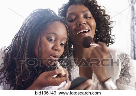 Stock Photo - Black mother and daughter putting on makeup. Fotosearch