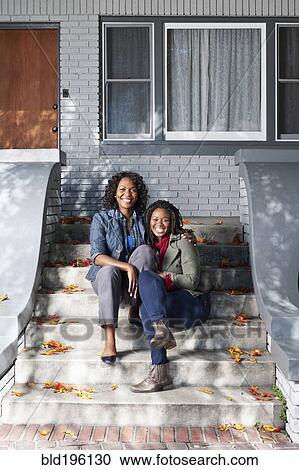 Stock Image - Black mother and daughter sitting on front stoop. Fotosearch