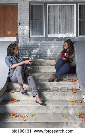 Black mother and daughter sitting on front stoop drinking wine View Large Photo Image Stock Image - Black mother and daughter sitting on front stoop drinking wine. Fotosearch
