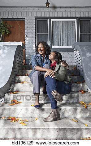 Stock Photo - Black mother and daughter sitting on front stoop. Fotosearch