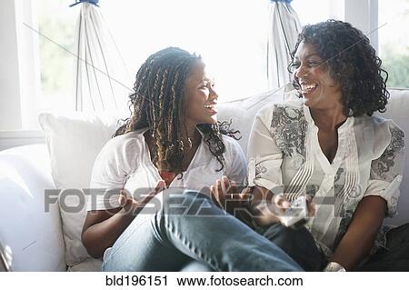 Stock Image - Black mother and daughter watching television together. Fotosearch