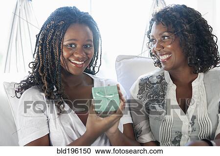 Black mother giving daughter gift View Large Photo Image Stock Image - Black mother giving daughter gift. Fotosearch