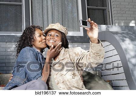 Stock Photo - Black mother taking self-portrait with soldier daughter. Fotosearch