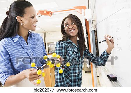 Stock Photo - Black teacher teaching student about chemistry model. Fotosearch