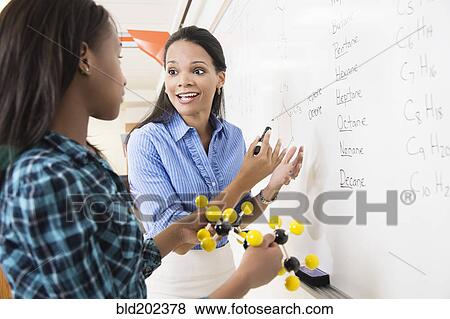 Stock Photo - Black teacher teaching student about chemistry model. Fotosearch