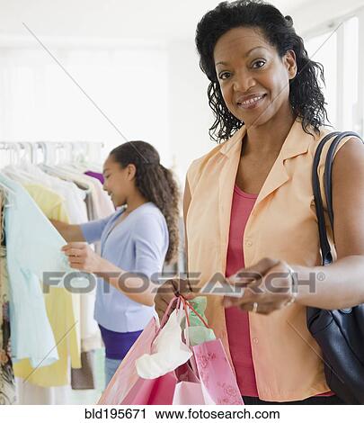 Black woman handing over credit card in clothing store View Large Photo Image Stock Image - Black woman handing over credit card in clothing store. Fotosearch