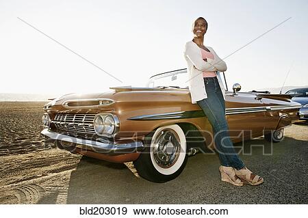 Stock Photo - Black woman leaning on convertible. Fotosearch
