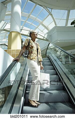 Stock Image - Black woman on mall escalator. Fotosearch