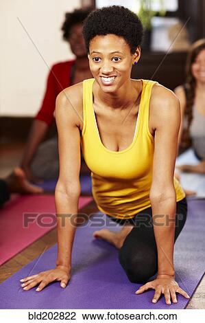 Stock Image - Black woman practicing yoga in class. Fotosearch