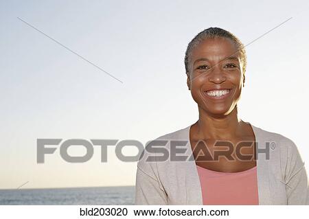 Stock Image - Black woman smiling outdoors. Fotosearch