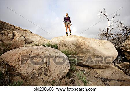 Stock Photograph - Black woman standing on top of rock. Fotosearch