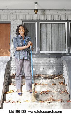 Stock Photo - Black woman sweeping front stoop steps. Fotosearch