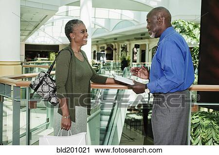 Stock Image - Black woman taking survey in shopping mall. Fotosearch