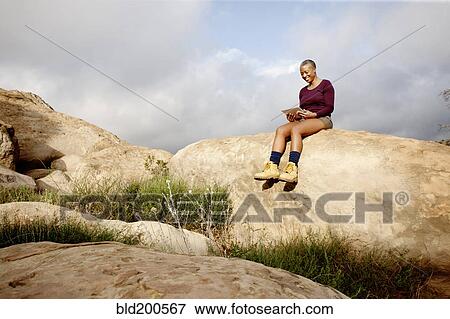 Black woman using digital tablet on rock View Large Photo Image Stock Photo - Black woman using digital tablet on rock. Fotosearch