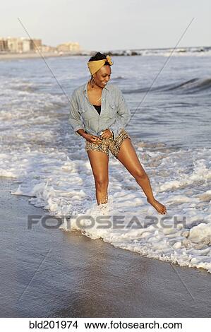 Black woman wading in ocean on beach View Large Photo Image Picture - Black woman wading in ocean on beach. Fotosearch