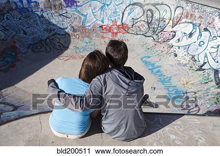 Stock Image - Boy and girl hugging in skateboard park. Fotosearch