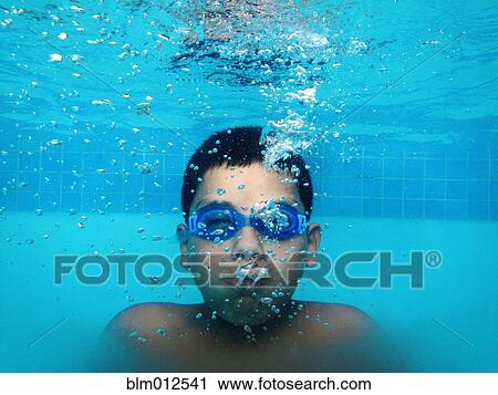 Stock Image - Boy holding his breath underwater in swimming pool. Fotosearch