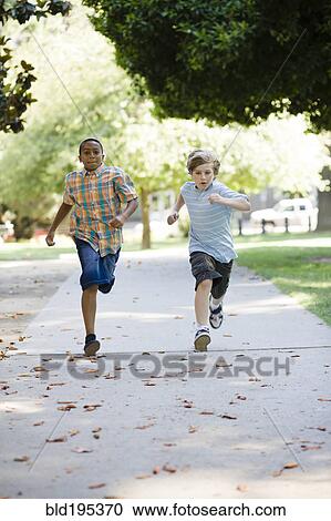 Stock Image - Boys running on sidewalk. Fotosearch