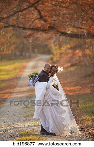 Stock Photo - Bride and groom hugging on path. Fotosearch