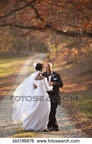 Stock Photograph - Bride and groom standing on path. Fotosearch